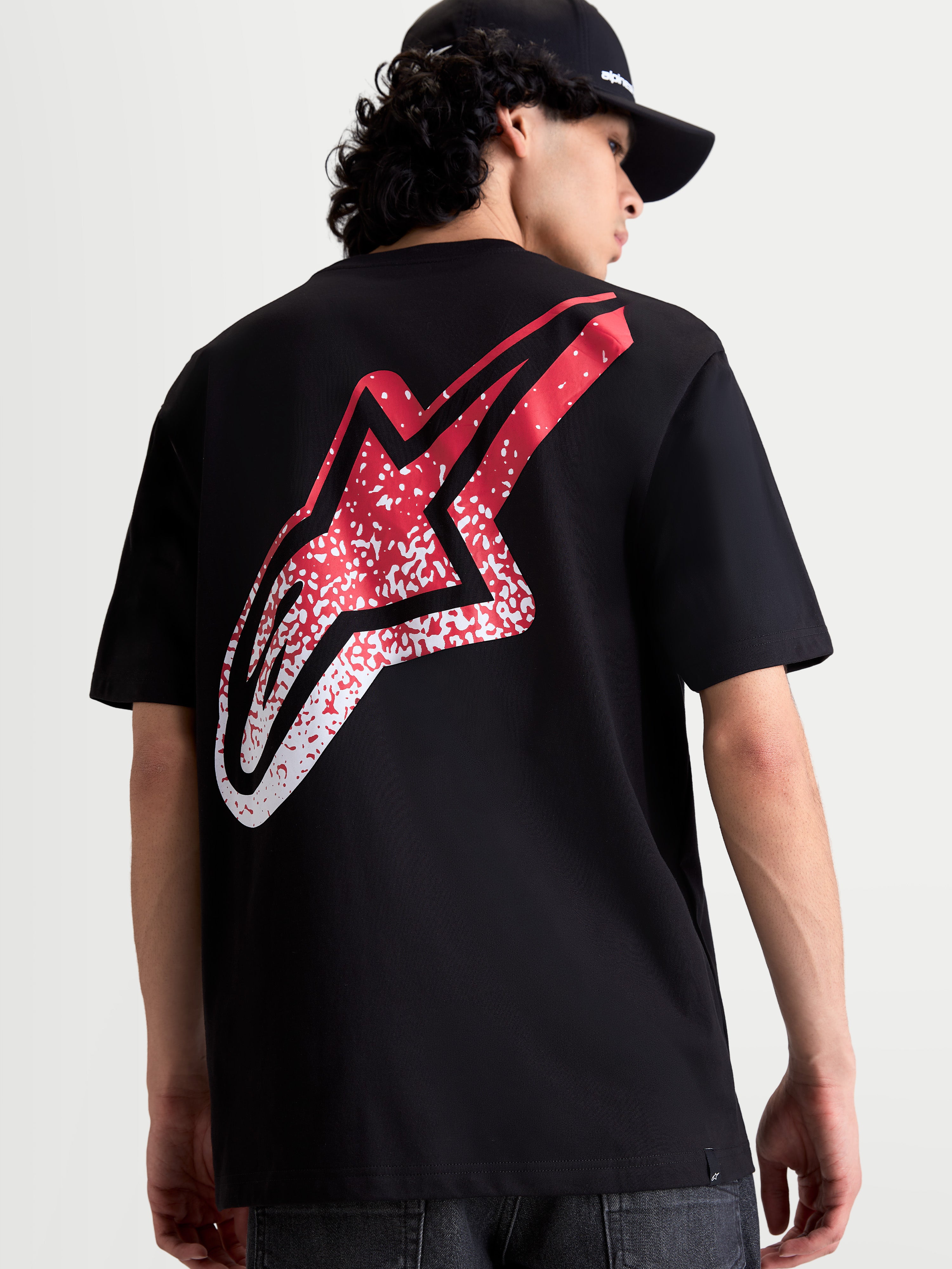 Alpinestars Koszulka Meteor CSF, czarna koszulka z krótkim rękawem, widok z tyłu na modelu, duża czerwono-biała grafika logo Astars z gradientem w stylu MX, casualowa odzież sportowa.
