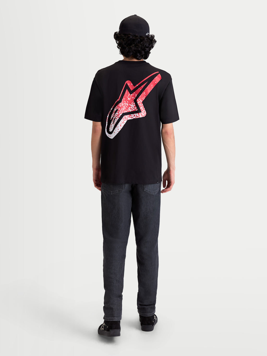 Alpinestars Meteor CSF Tee, czarna koszulka z krótkim rękawem, widok z tyłu na modelu, duże logo Astars na plecach z czerwono-białym gradientem w stylu MX, casualowa odzież sportowa.