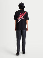 Alpinestars Meteor CSF Tee, czarna koszulka z krótkim rękawem, widok z tyłu na modelu, duże logo Astars na plecach z czerwono-białym gradientem w stylu MX, casualowa odzież sportowa.
