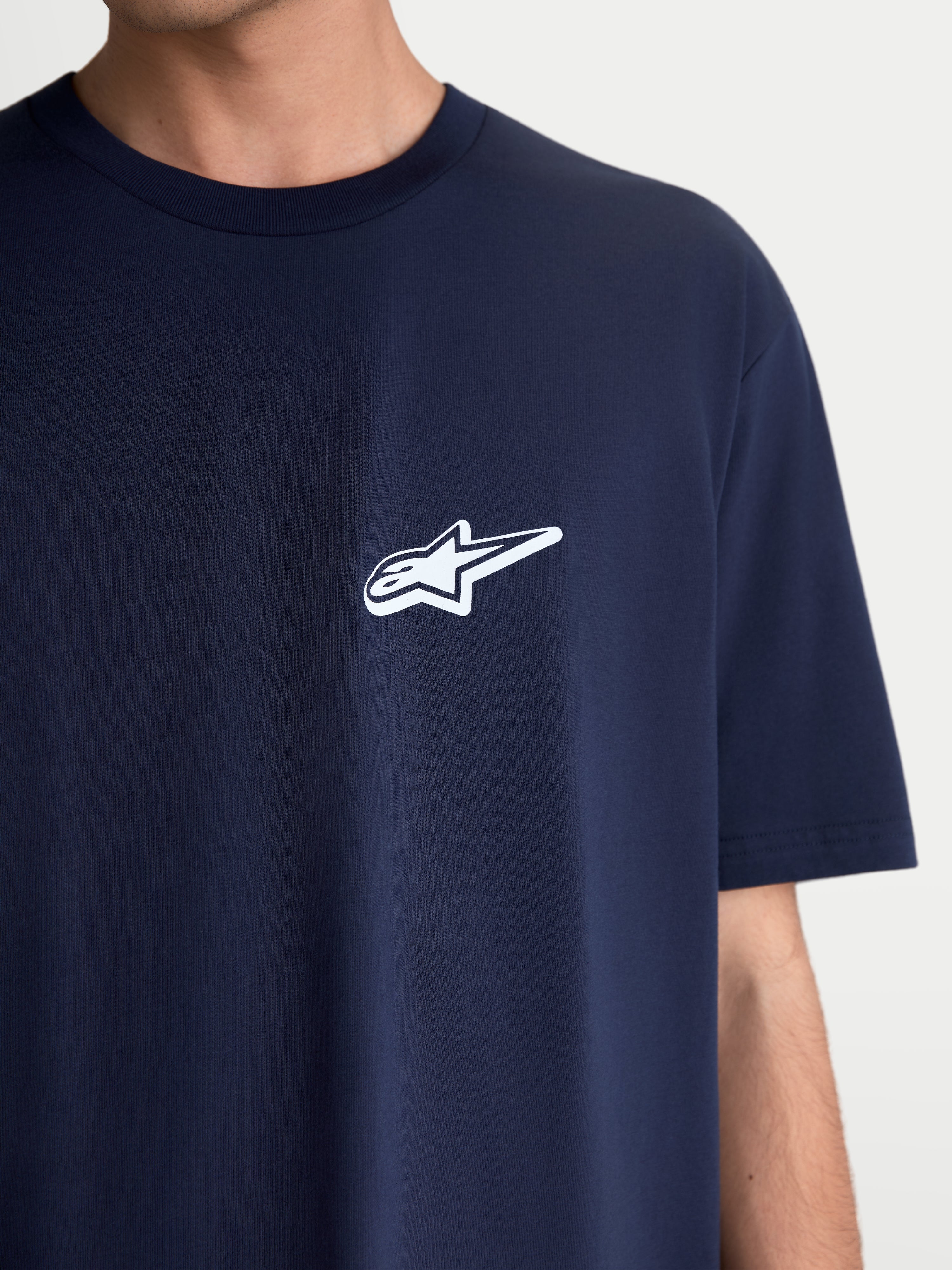 Alpinestars Koszulka Meteor CSF, koszulka sportowa z krótkim rękawem, granatowa z białym logo Astars na piersi, codzienna odzież motorsportowa unisex, miękka mieszanka bawełny i poliestru, zbliżenie na modelu.