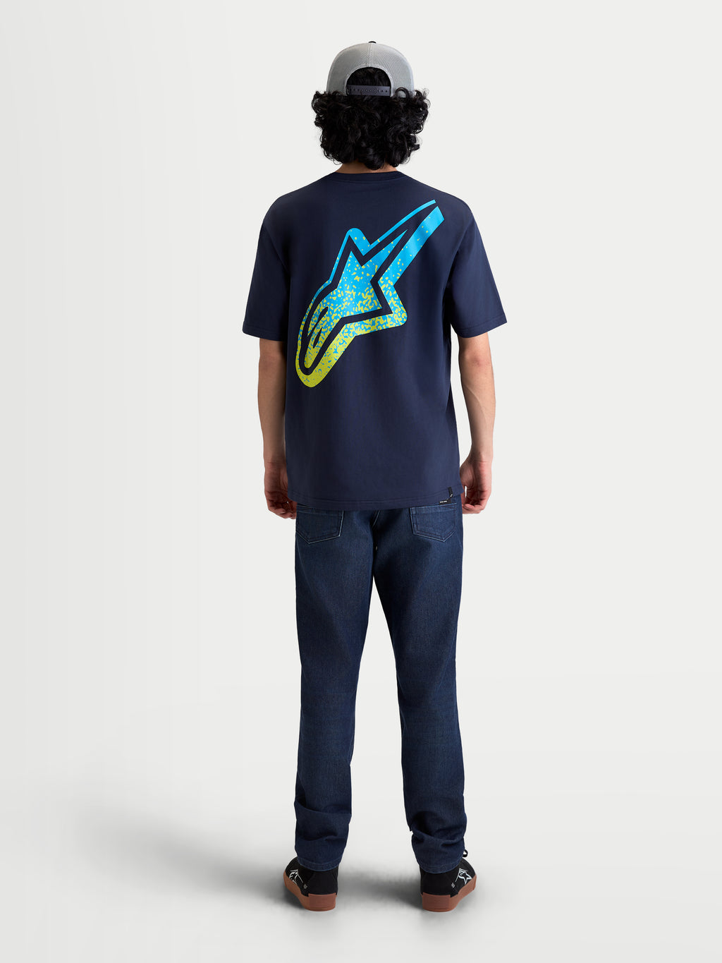 Alpinestars Koszulka Meteor CSF, granatowa koszulka z krótkim rękawem, widok z tyłu na modelu, duże żółte i niebieskie gradientowe logo Astars na plecach, miękka mieszanka bawełny i poliestru, casualowa odzież sportowa.