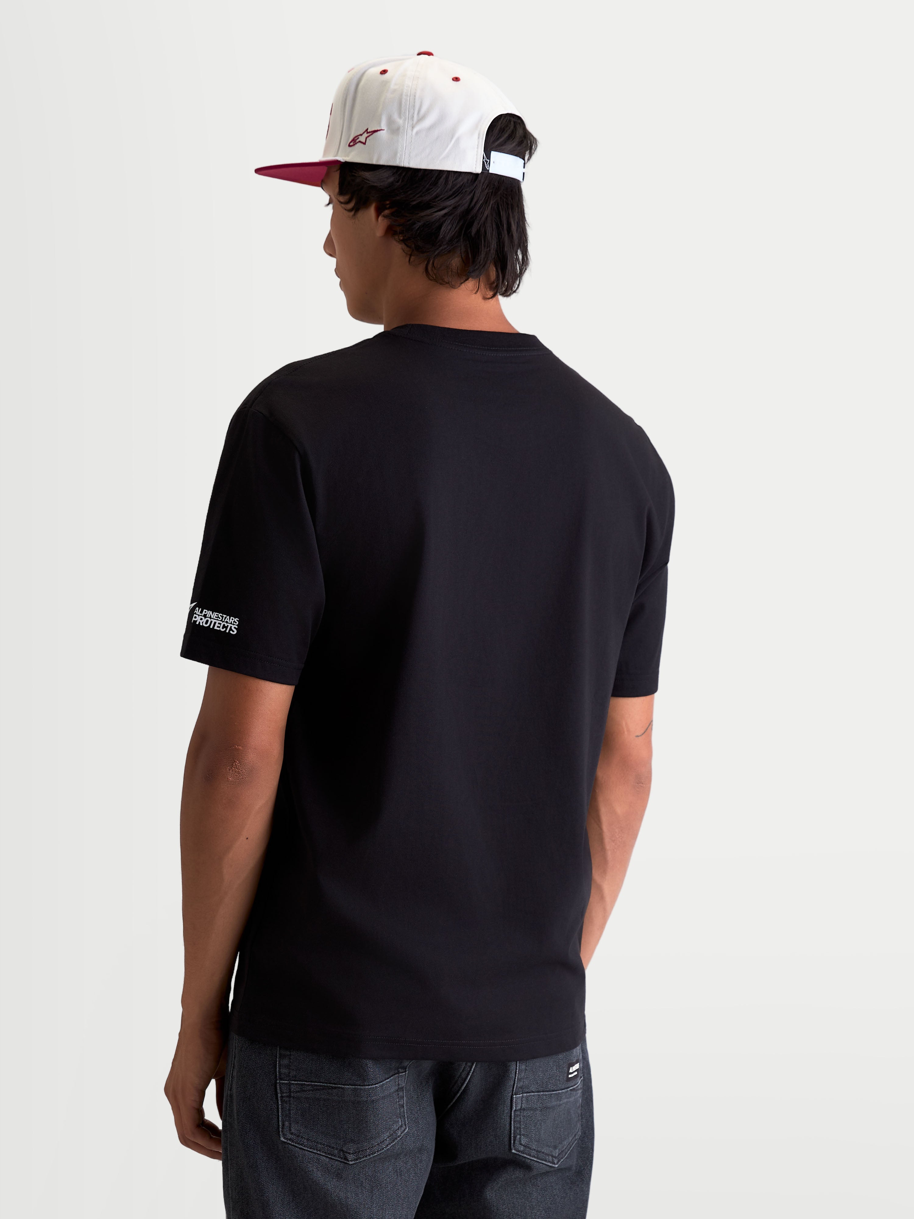 Alpinestars P1 CSF Tee, czarna koszulka z krótkim rękawem, odzież sportowa unisex w stylu motorsport, widok z tyłu na modelu, logo Alpinestars Protects na rękawie.