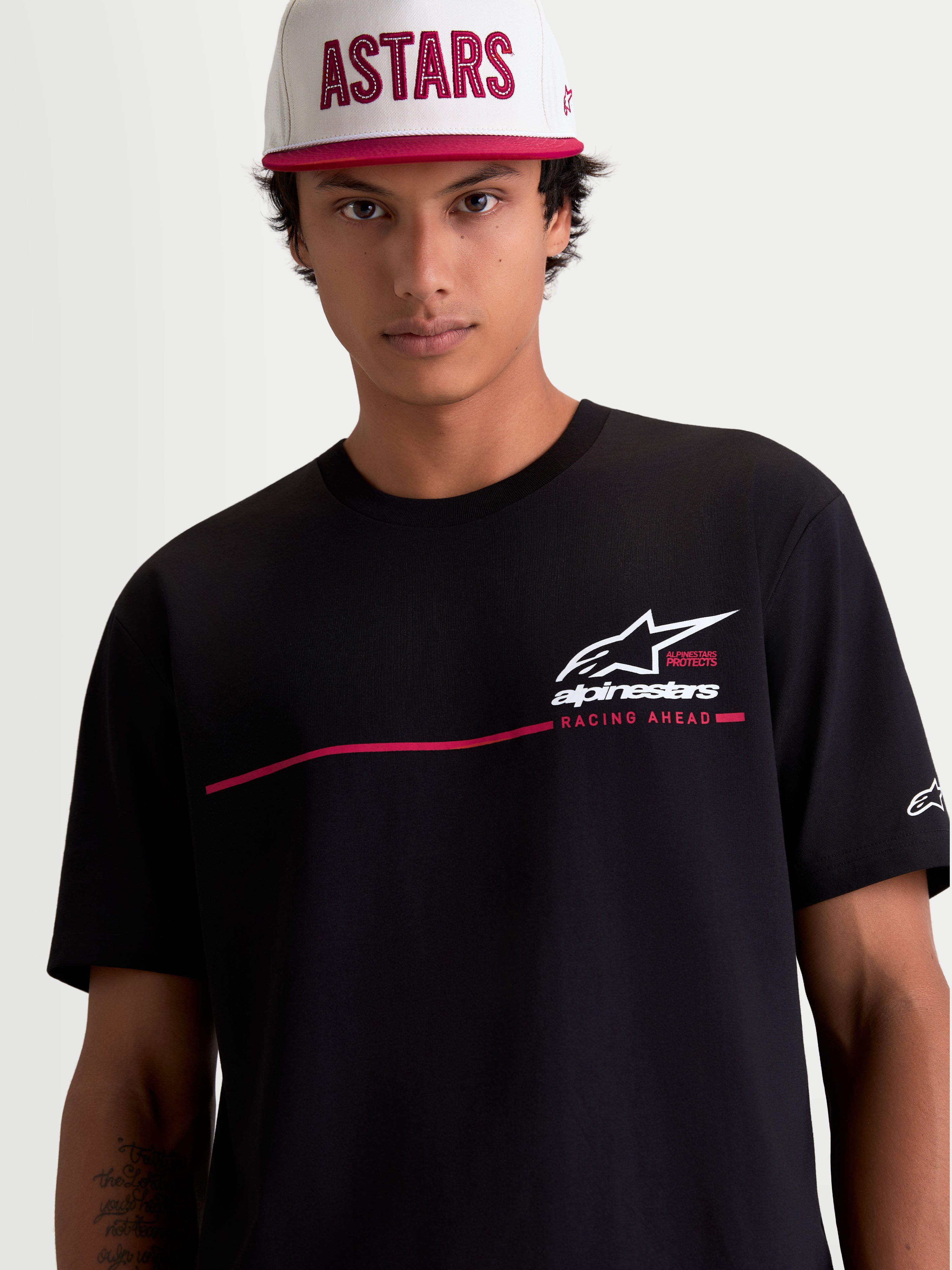 Alpinestars P1 CSF, czarna koszulka z krótkim rękawem, białe logo i czerwony pasek wyścigowy, t-shirt sportswear unisex z mieszanki bawełny i poliestru, model na zdjęciu