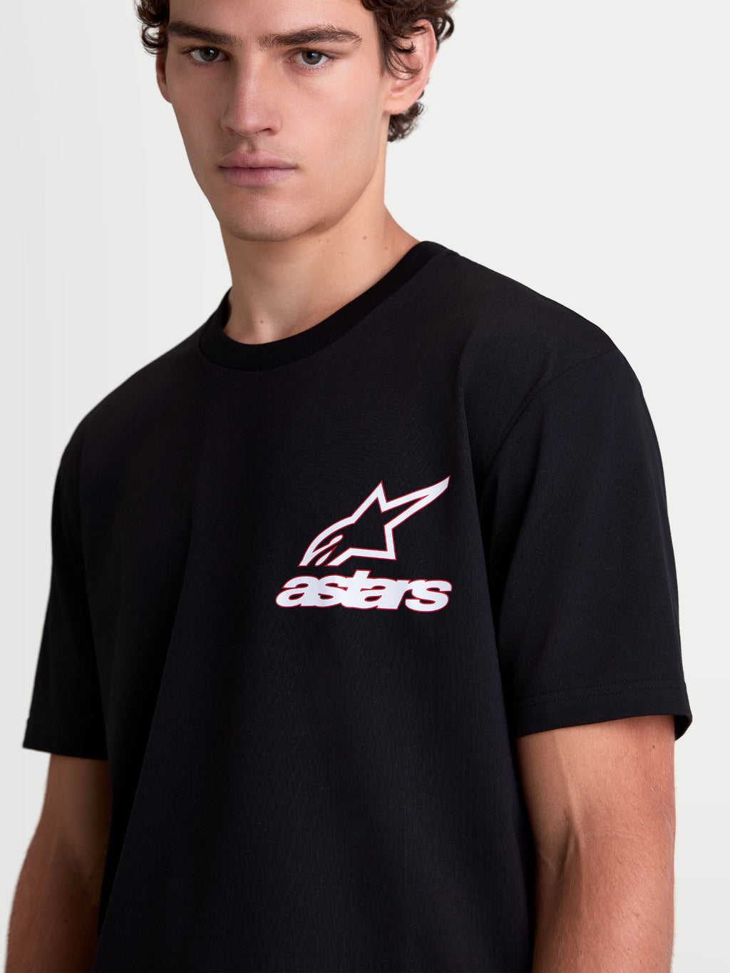 Alpinestars Koszulka Lineout CSF, koszulka sportowa z krótkim rękawem na modelu, czarna z biało-czerwoną grafiką logo Astars na klatce piersiowej, casualowa odzież lifestyle, mieszanka bawełny i poliestru