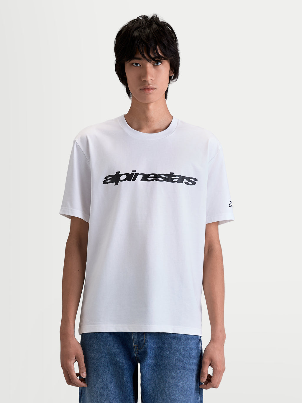 Alpinestars Race Wordmark CSF, biała koszulka z krótkim rękawem, czarny wyrazisty logotyp race na piersi, logo na rękawie, styl motorsportowy, premium mieszanka bawełny i poliestru, widok z przodu na modelu.