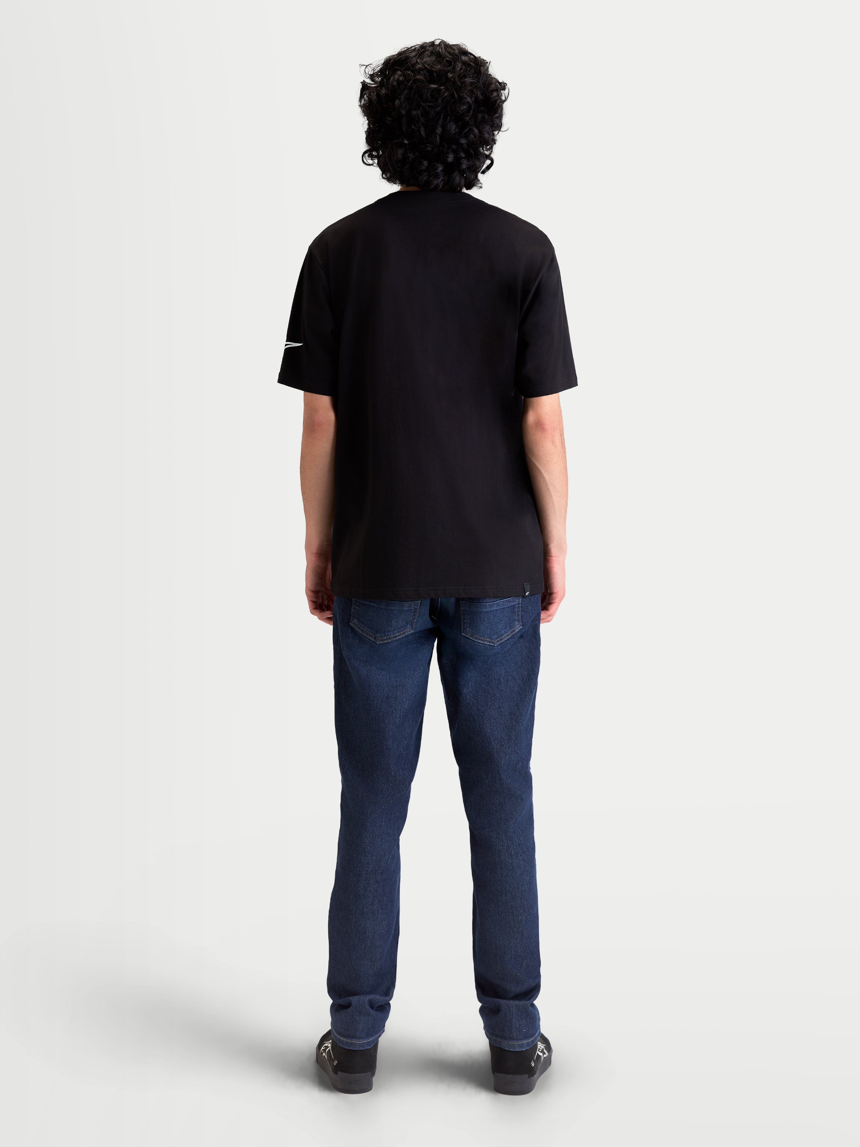 Alpinestars Race Wordmark CSF Tee, Black Short Sleeve Sportswear T-Shirt, back view on model, featuring a white Ageless logo on the sleeve. Casual motorsport-inspired apparel made from a soft cotton-poly blend.