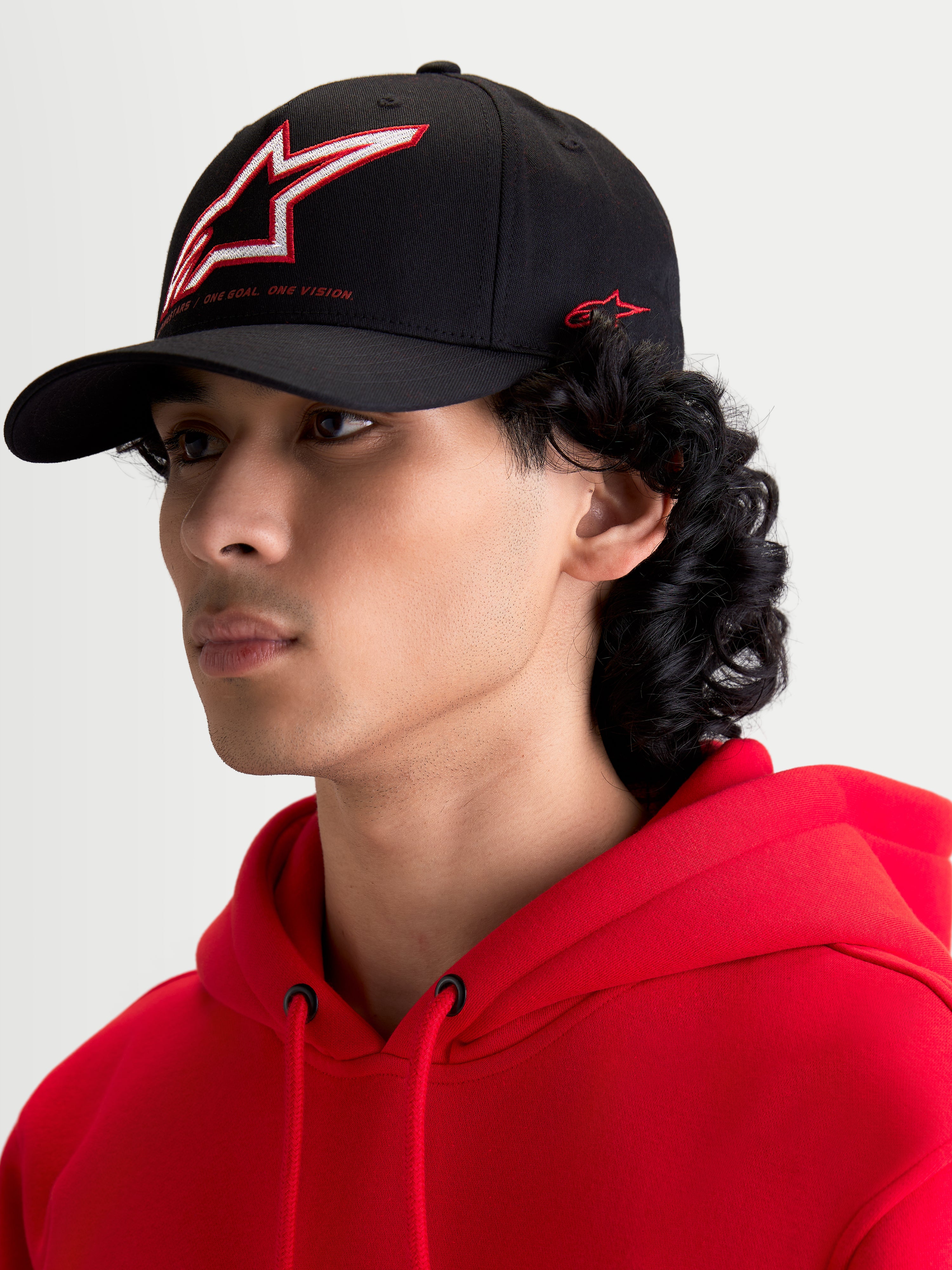 Alpinestars Czapka Lineout, czarna czapka z daszkiem, odzież sportowa, usztywniona korona z czerwono-białym haftowanym logo Astars i bocznym brandingiem, produkt z zakrzywionym daszkiem prezentowany na modelu.