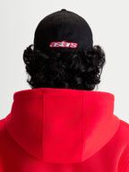 Alpinestars Czapka Lineout, czapka z daszkiem typu baseball, sportswear, czarna i czerwona, widok z tyłu na modelu, haftowane logo astars, usztywniona korona, konstrukcja z tkaniny twill