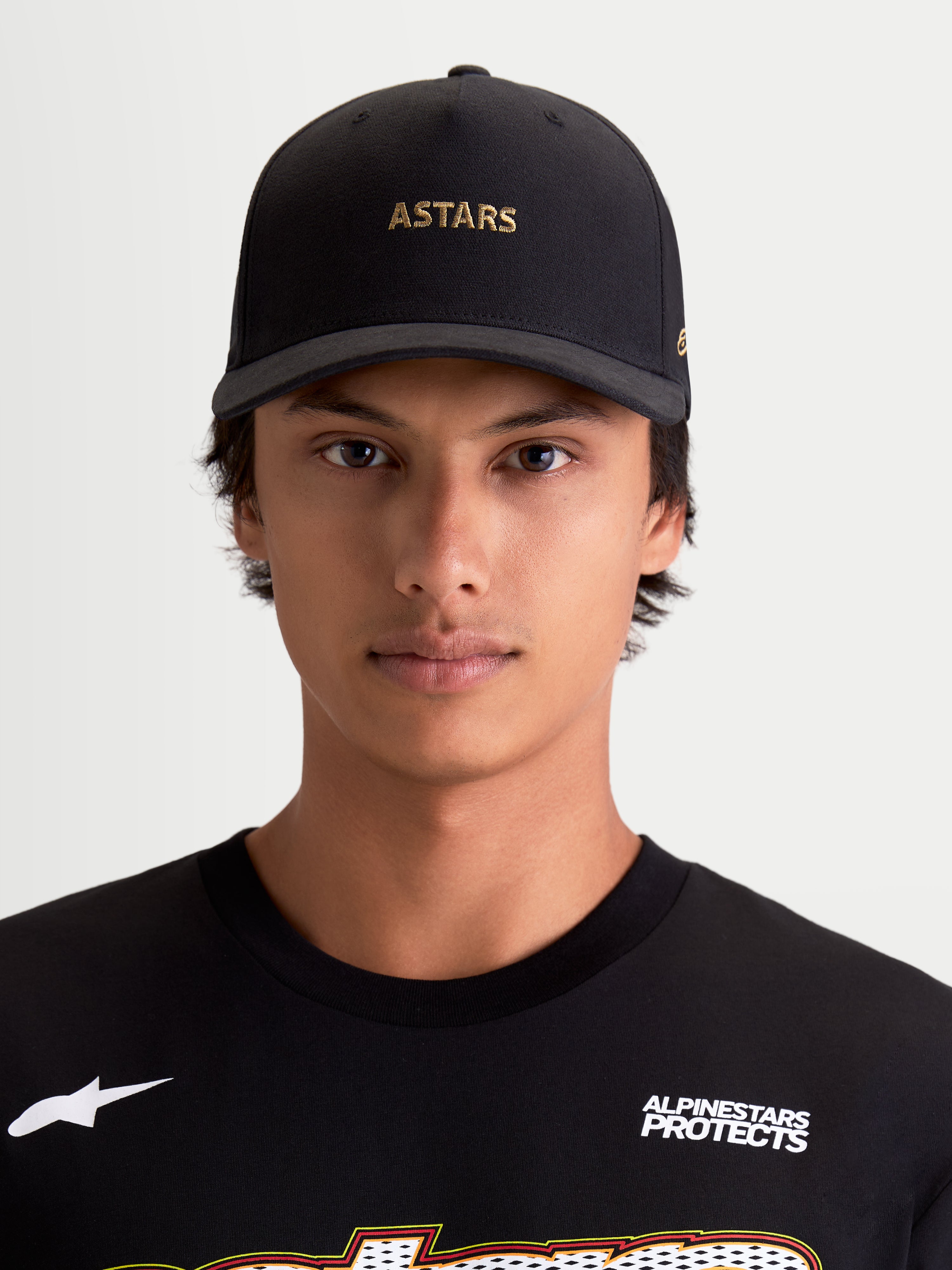 Alpinestars czapka z daszkiem County Canvas, sportowa czapka bejsbolówka z zakrzywionym daszkiem, czarna ze złotym haftem logo ASTARS, tkanina oxford peached i usztywniona korona, codzienna odzież lifestyle na modelu.