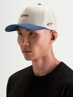 Alpinestars County Canvas Hat, czapka z daszkiem sportswear w kolorze piaskowym i niebieskim, na modelce, z zakrzywionym daszkiem i haftowanym logo Astars