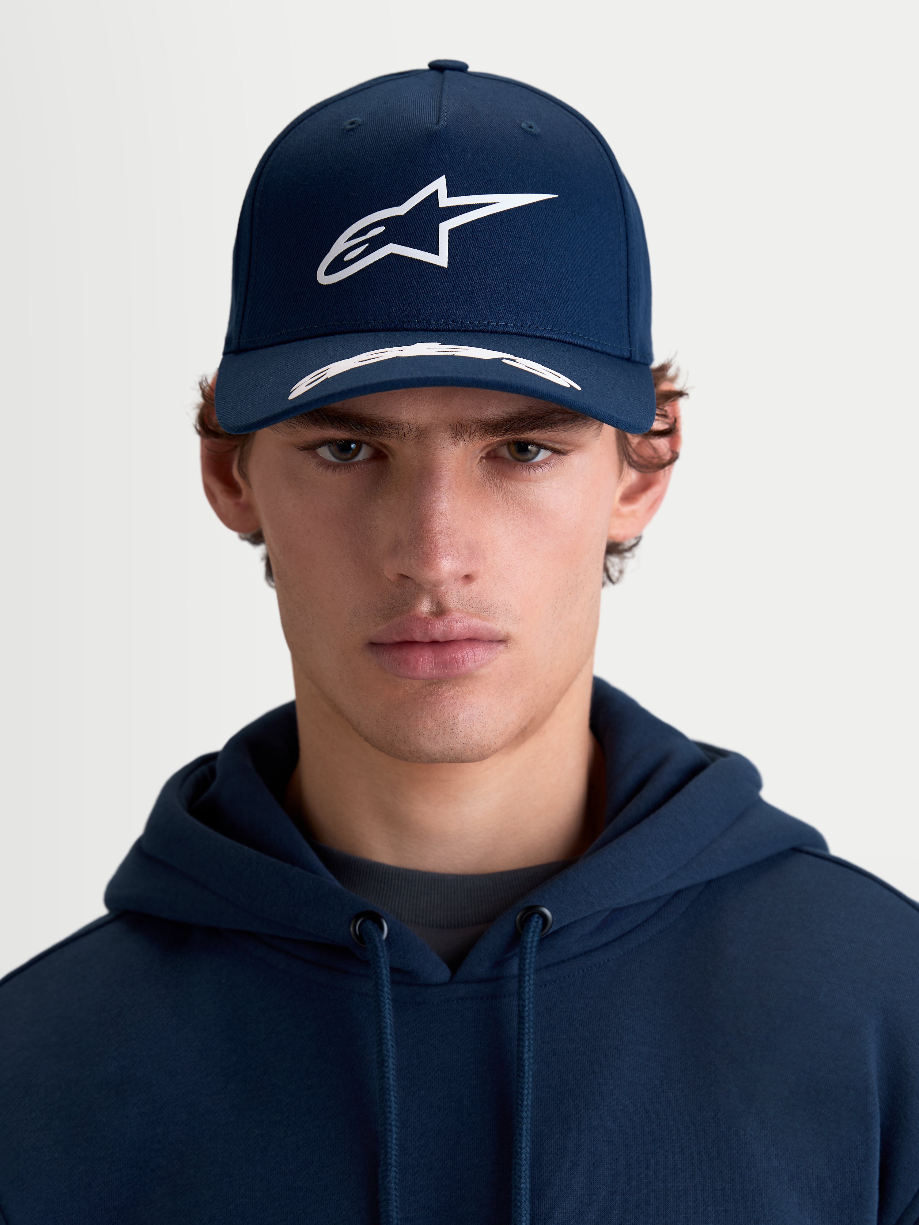 Alpinestars Arclight Hat, czapka z daszkiem sportswear, granatowa i biała, widok z przodu na modelu, usztywniona korona, zakrzywiony daszek, logo Astars w nadruku puff print, bawełniany kepr premium.