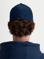 Alpinestars Arclight Hat, granatowa czapka z daszkiem, sportowa odzież unisex, wytrzymała tkanina keprowa, elastyczny tył flex back, widok z tyłu na modelu z widoczną metką z logo Astars.