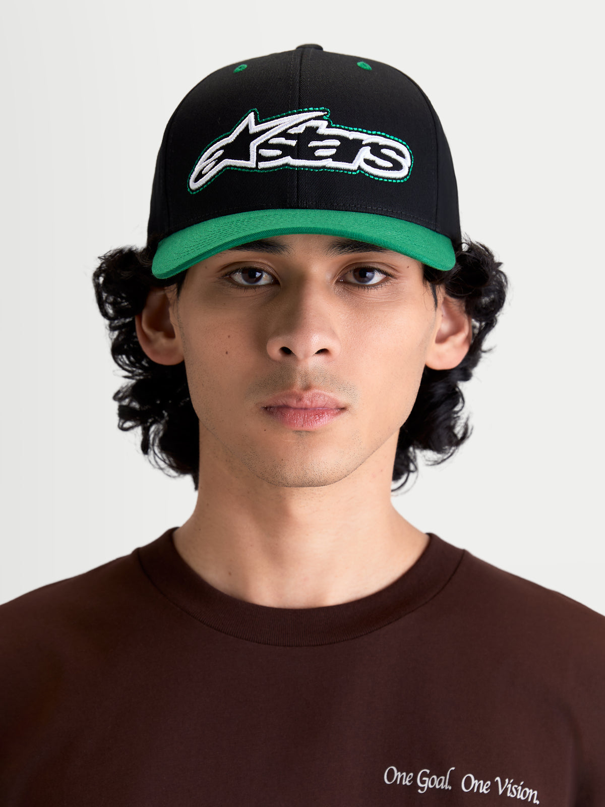 Alpinestars Retro Snapback, czapka lifestyle sportswear, czarna i zielona, z zakrzywionym daszkiem i usztywnioną koroną, haftowane logo Astars z przodu z zielonym ściegiem, widok na modelu z przodu.