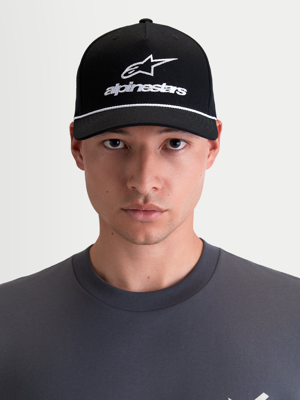 Alpinestars Czapka Combo Logo Snapback, motorsportowa czapka z daszkiem unisex, czarna i biała, zakrzywiony daszek, usztywniona korona, haftowane logo Astars, keper bawełniany, widok z przodu na modelu.