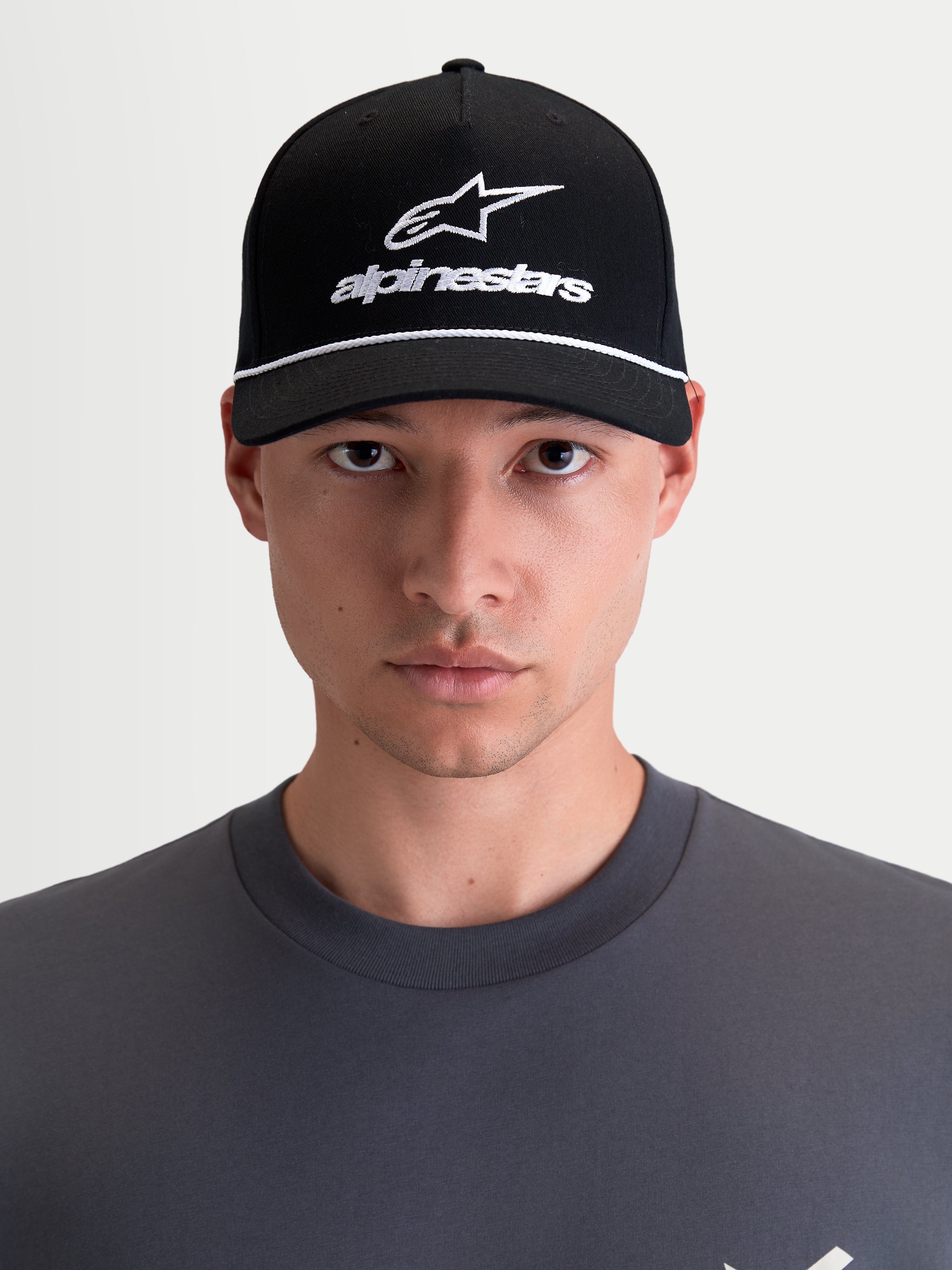 Alpinestars Czapka Combo Logo Snapback, motorsportowa czapka z daszkiem unisex, czarna i biała, zakrzywiony daszek, usztywniona korona, haftowane logo Astars, keper bawełniany, widok z przodu na modelu.