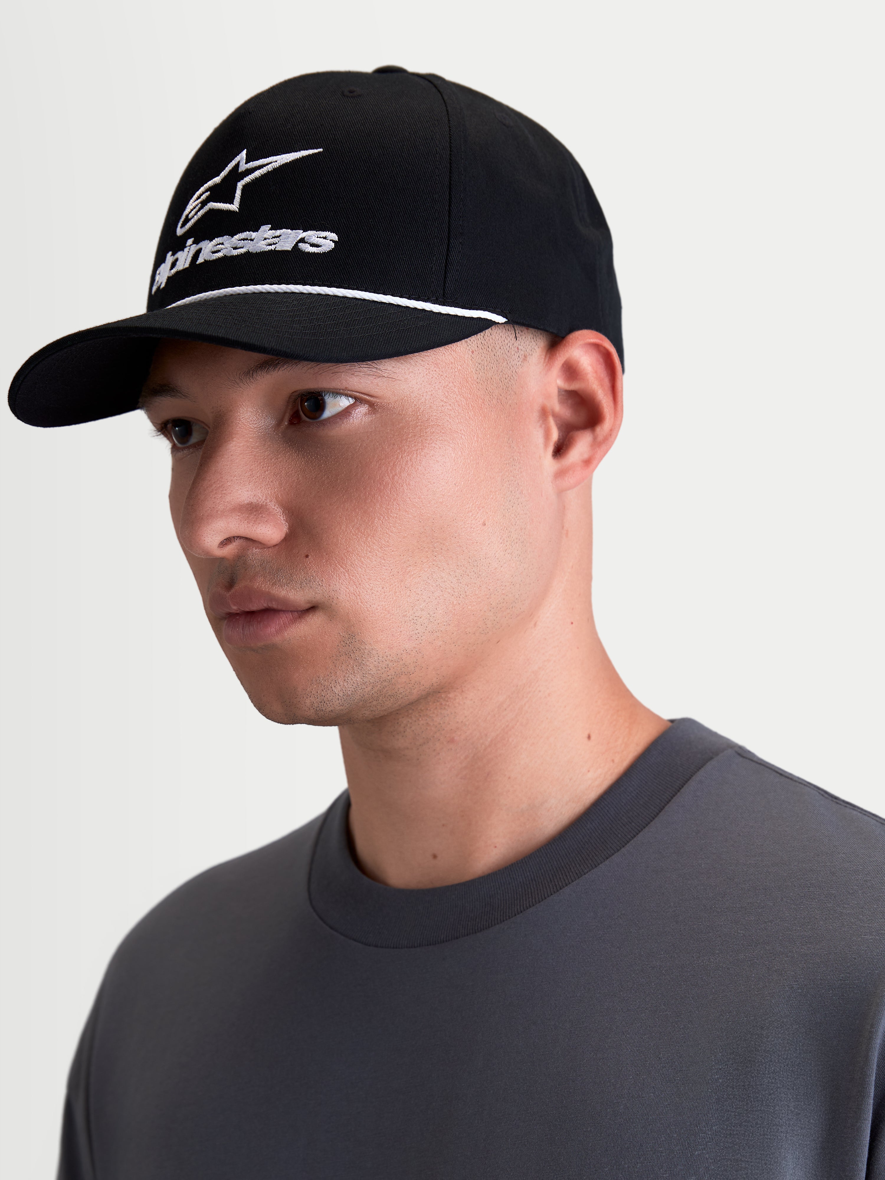Alpinestars Combo Logo Snapback, czarna i biała czapka z daszkiem lifestyle, zakrzywiony daszek, usztywniona korona, biały haft z logo Alpinestars i ozdobny sznurek, widok na modelu z profilu.