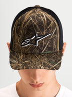 Alpinestars Czapka Z Daszkiem Thicket Realtree, czapka z daszkiem typu trucker w kamuflażu Realtree i czarnym kolorze, na modelu, z usztywnioną koroną i białym haftowanym logo Astars na froncie
