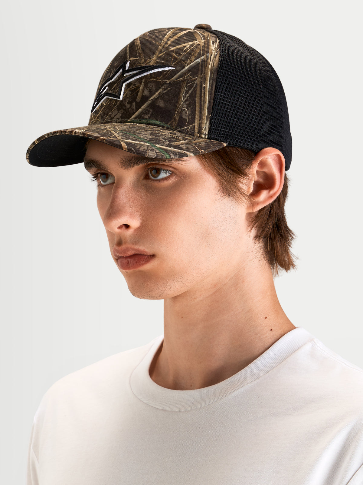 Alpinestars Czapka Z Daszkiem Thicket Realtree, czapka trucker sportswear w kamuflażu Realtree i czarnym, z zakrzywionym daszkiem, usztywnioną koroną i haftowanym logo Astars 3D, na modelu