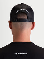 Alpinestars czapka z daszkiem Meteorite, czarna i biała czapka typu trucker, widok z tyłu na regulowane zapięcie snapback i białe haftowane logo Alpinestars, siatkowy tył, odzież sportswear.