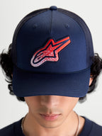 Alpinestars Czapka Z Daszkiem Meteorite, granatowa czapka z daszkiem, czerwone i białe logo Astars o fakturze żwiru, usztywniona korona i zakrzywiony daszek, widok z przodu na modelu.