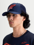Alpinestars Czapka Z Daszkiem Meteorite, sportowa czapka z siatką typu trucker, granatowa z czerwonym logo Astars o teksturze żwiru, zakrzywiony daszek i usztywniona korona, widok na modelu.