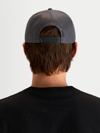Alpinestars Ten Trucker Hat, czapka z daszkiem w kolorze ciemnoszarym, widok z tyłu na model prezentujący regulowane zapięcie snapback, tylne panele z siatki oraz detale z logo