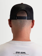 Alpinestars czapka z daszkiem Hotlink, czapka typu trucker, styl sportowy lifestyle, unisex, brązowa i czarna, widok z tyłu na modelu, regulowane zapięcie snapback, siateczkowe panele tylne dla lepszej oddychalności, detale brandingowe premium.