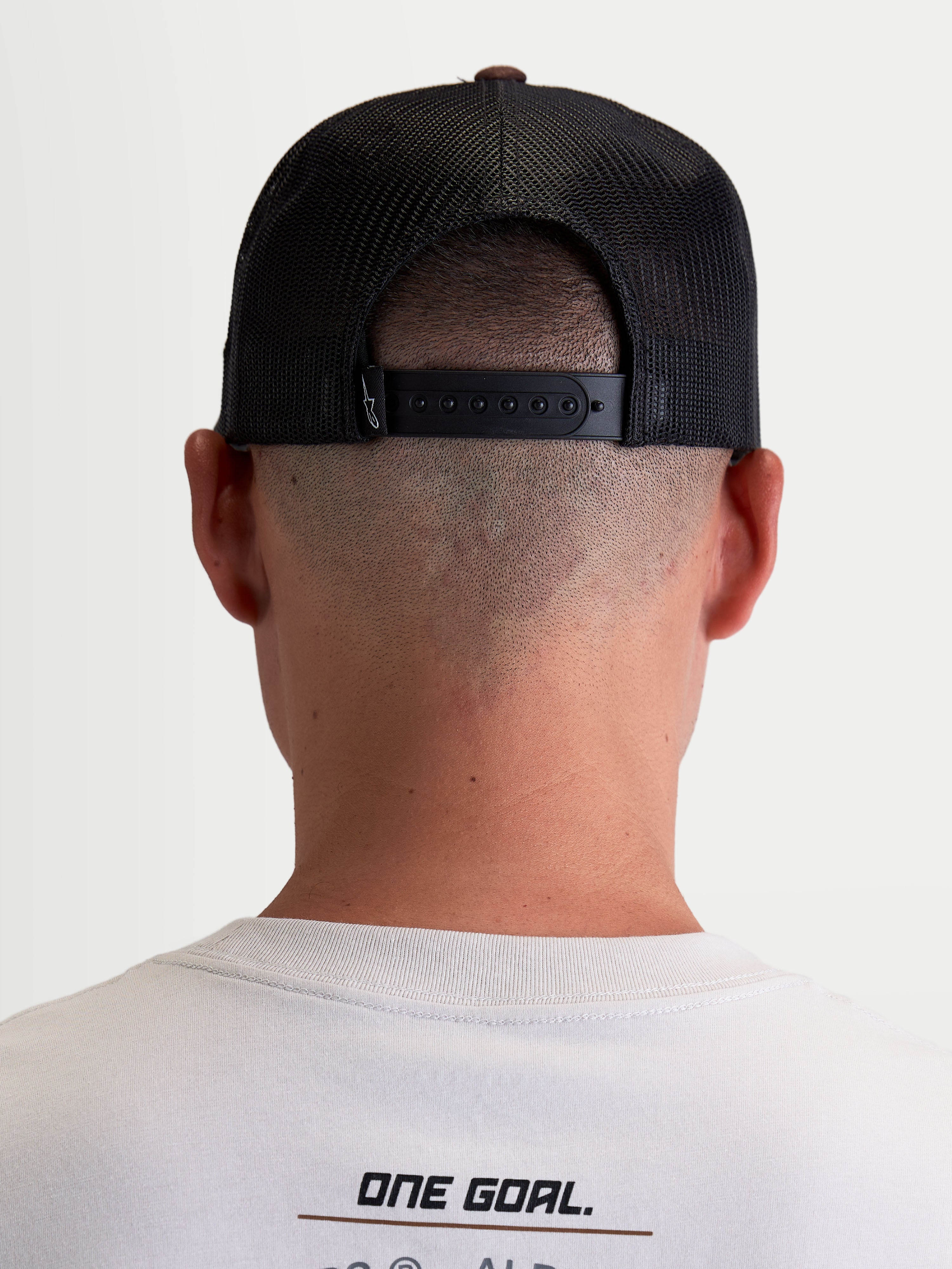 Alpinestars czapka z daszkiem Hotlink, czapka typu trucker, styl sportowy lifestyle, unisex, brązowa i czarna, widok z tyłu na modelu, regulowane zapięcie snapback, siateczkowe panele tylne dla lepszej oddychalności, detale brandingowe premium.