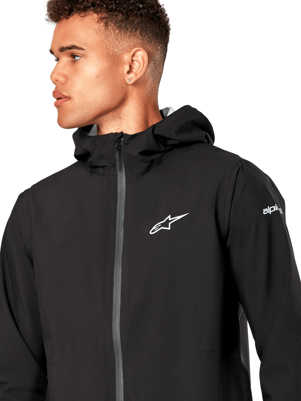 Alpinestars Kascade Rain Jacket, czarna kurtka przeciwdeszczowa typu shell, z białym logo gwiazdy na piersi, stałym kapturem i powlekanym odwróconym zamkiem błyskawicznym z przodu, codzienna odzież wyczynowa inspirowana motorsportem