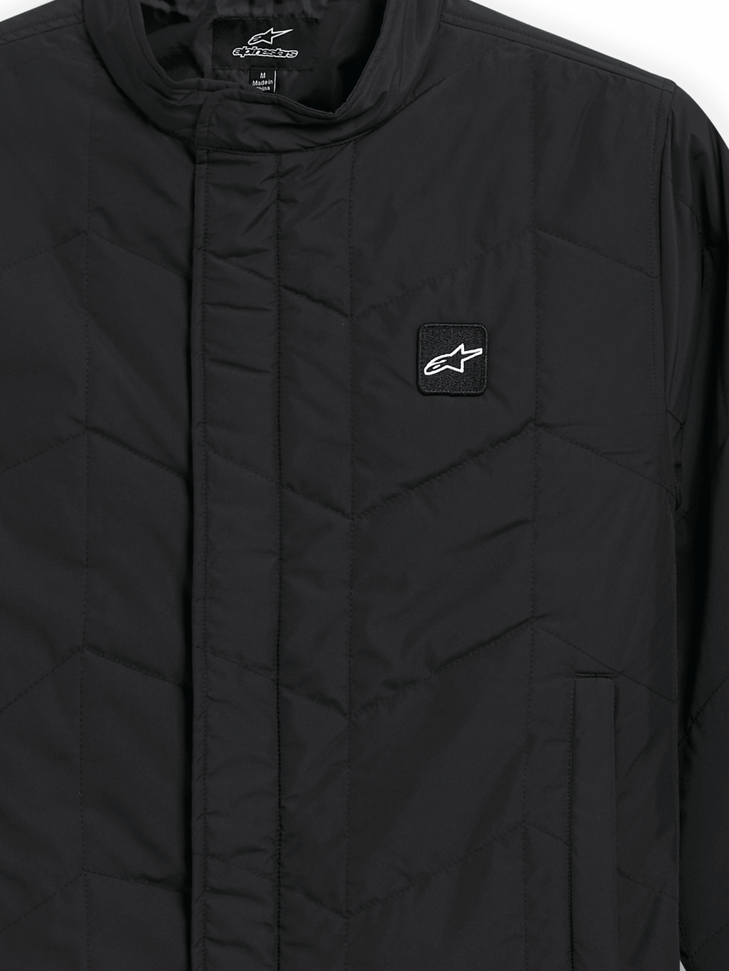 Alpinestars Precedent Jacket, pikowana kurtka sportowa, czarna, zbliżenie na kultowy skośny wzór pikowania, niski kołnierz torowy, zakryty przedni zamek i mała naszywka z logo na piersi
