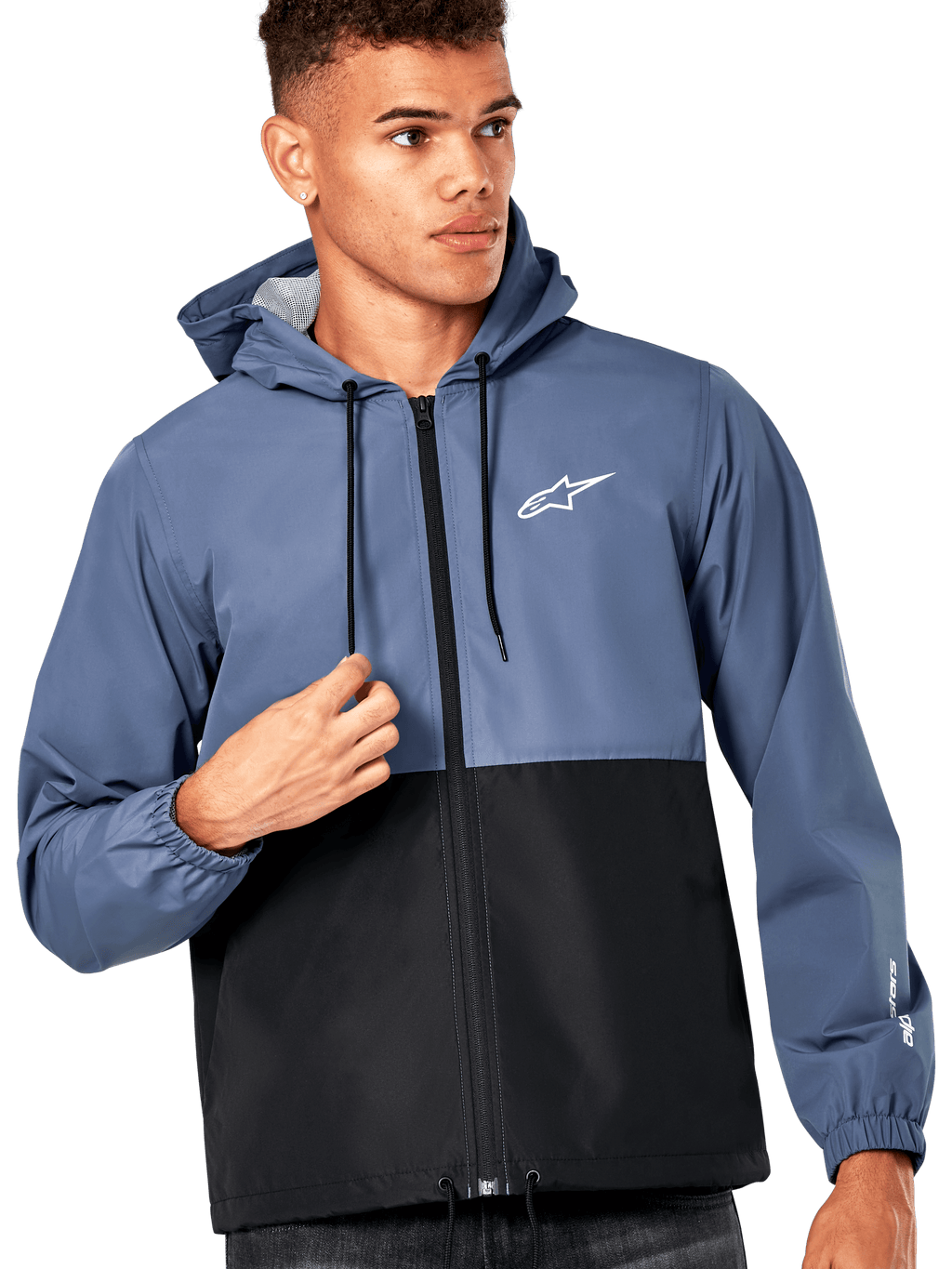 Męski model w kurtce Alpinestars Speeder Windbreaker Jacket, niebiesko-czarny design typu color-block, z kapturem i czarnymi sznurkami, białe logo na piersi, casualowa wiatrówka inspirowana sportami motorowymi