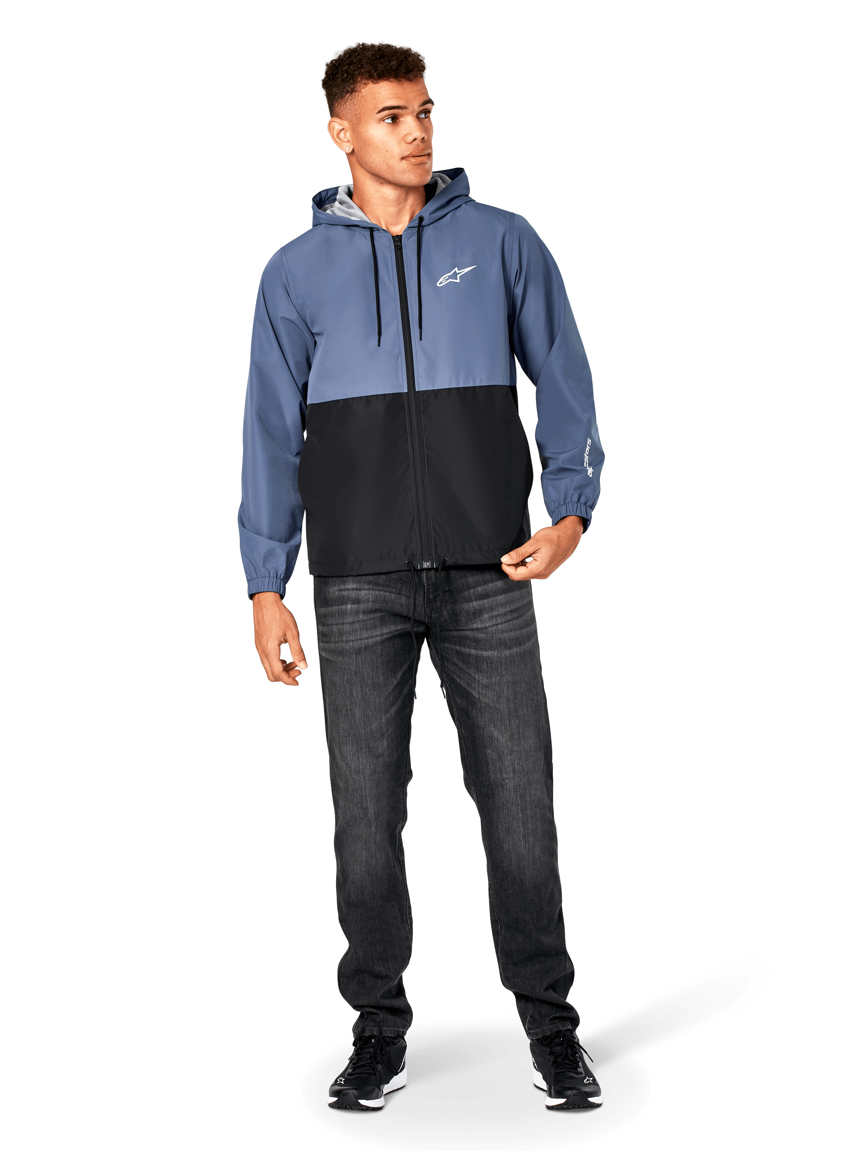 Kurtka Alpinestars Speeder Windbreaker, stalowoniebieska i czarna, lekka wiatrówka z kapturem i siatkową podszewką, białe logo z gwiazdą na piersi, noszona z czarnymi dżinsami i sneakersami, casualowy design w stylu motorsport streetwear.