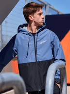 Alpinestars Speeder Windbreaker Jacket, lekka wiatrówka z kapturem, niebiesko-czarna konstrukcja typu color-block, białe logo Alpinestars na klatce piersiowej, podszewka z siatki i kaptur regulowany sznurkiem, casualowy streetwear inspirowany motorsportem