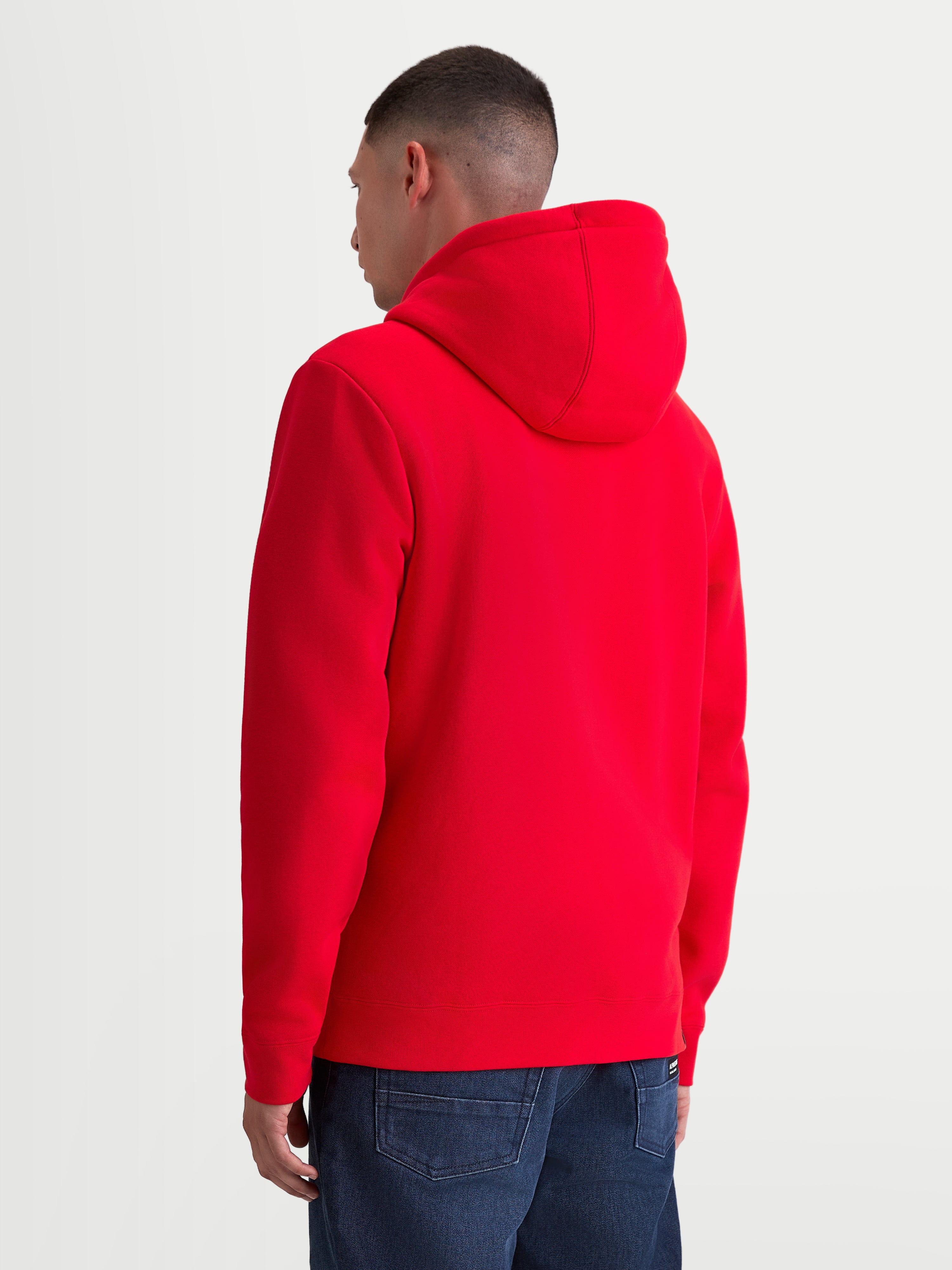 Alpinestars Bluza Z Kapturem Ageless Zip V3, męska bluza polarowa, czerwona, widok z tyłu na modelu, wyposażona w wygodny kaptur i ściągacz u dołu, zaprojektowana dla motocyklistów i fanów motorsportu.