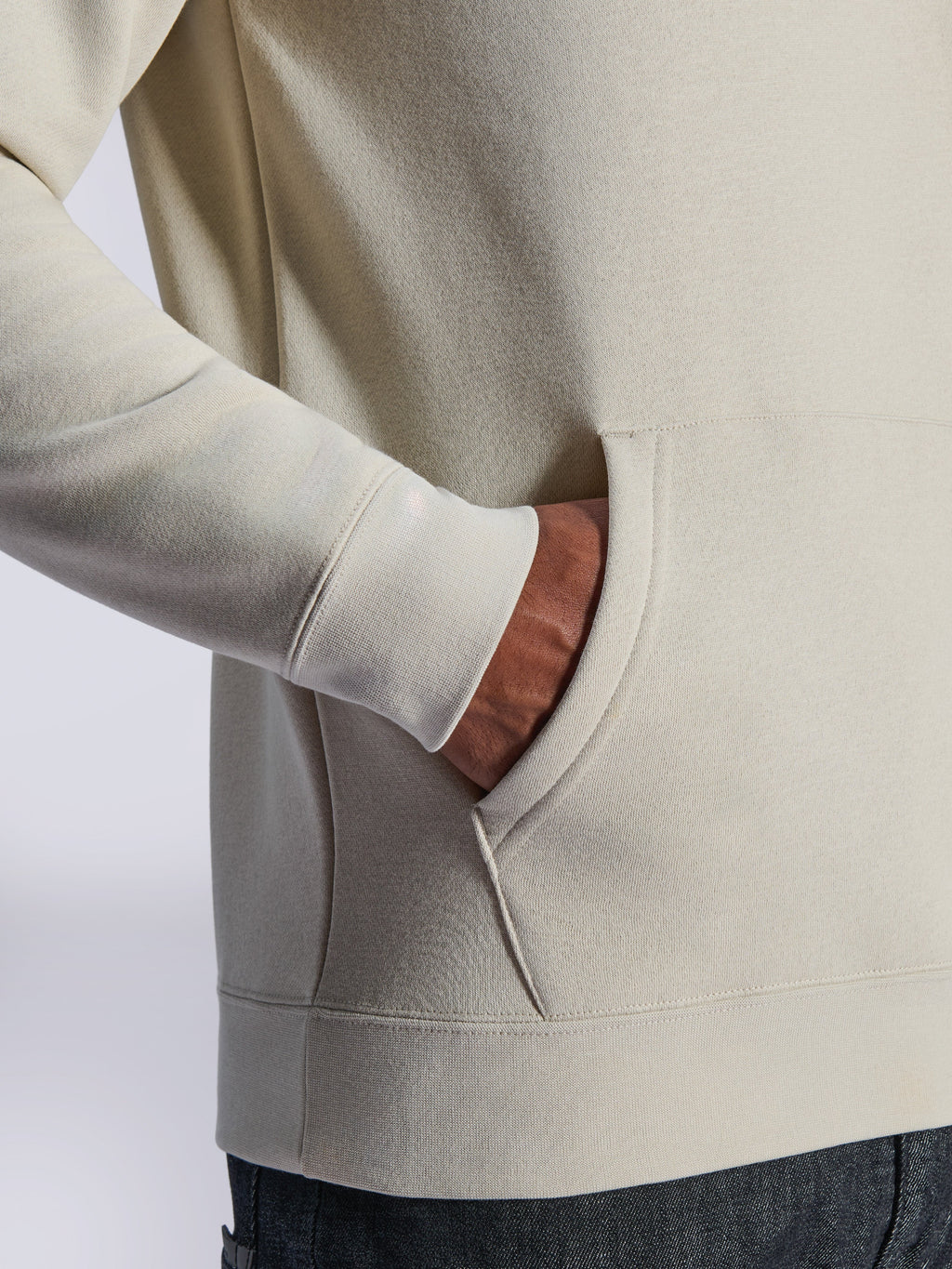Alpinestars Ageless V3 Hoodie, zbliżenie na przednią kieszeń typu kangurka i prążkowany mankiet, polar w kolorze off-white, casualowy streetwear inspirowany sportami motorowymi