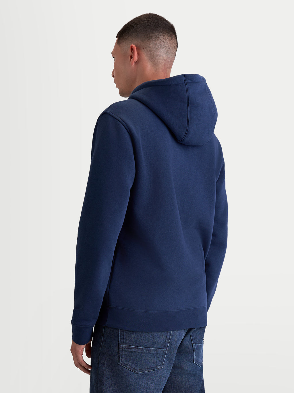 Alpinestars Bluza Z Kapturem Ageless V3, granatowa bluza sportowa typu pullover z polaru, widok z tyłu na modelu, wyposażona w kaptur z podszewką oraz ściągacze przy mankietach i u dołu, wykonana z bawełny premium i poliestru z recyklingu.