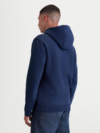 Alpinestars Bluza Z Kapturem Ageless V3, granatowa bluza sportowa typu pullover z polaru, widok z tyłu na modelu, wyposażona w kaptur z podszewką oraz ściągacze przy mankietach i u dołu, wykonana z bawełny premium i poliestru z recyklingu.