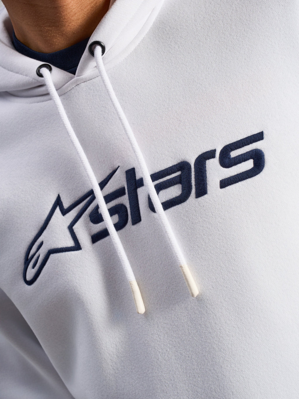 Alpinestars Blaze V3 Hoodie, biało-granatowa, zbliżenie na klatkę piersiową z granatowym nadrukiem logo z przodu i białymi sznurkami z powlekanymi końcówkami, codzienna odzież streetwearowa w stylu motorsportowym
