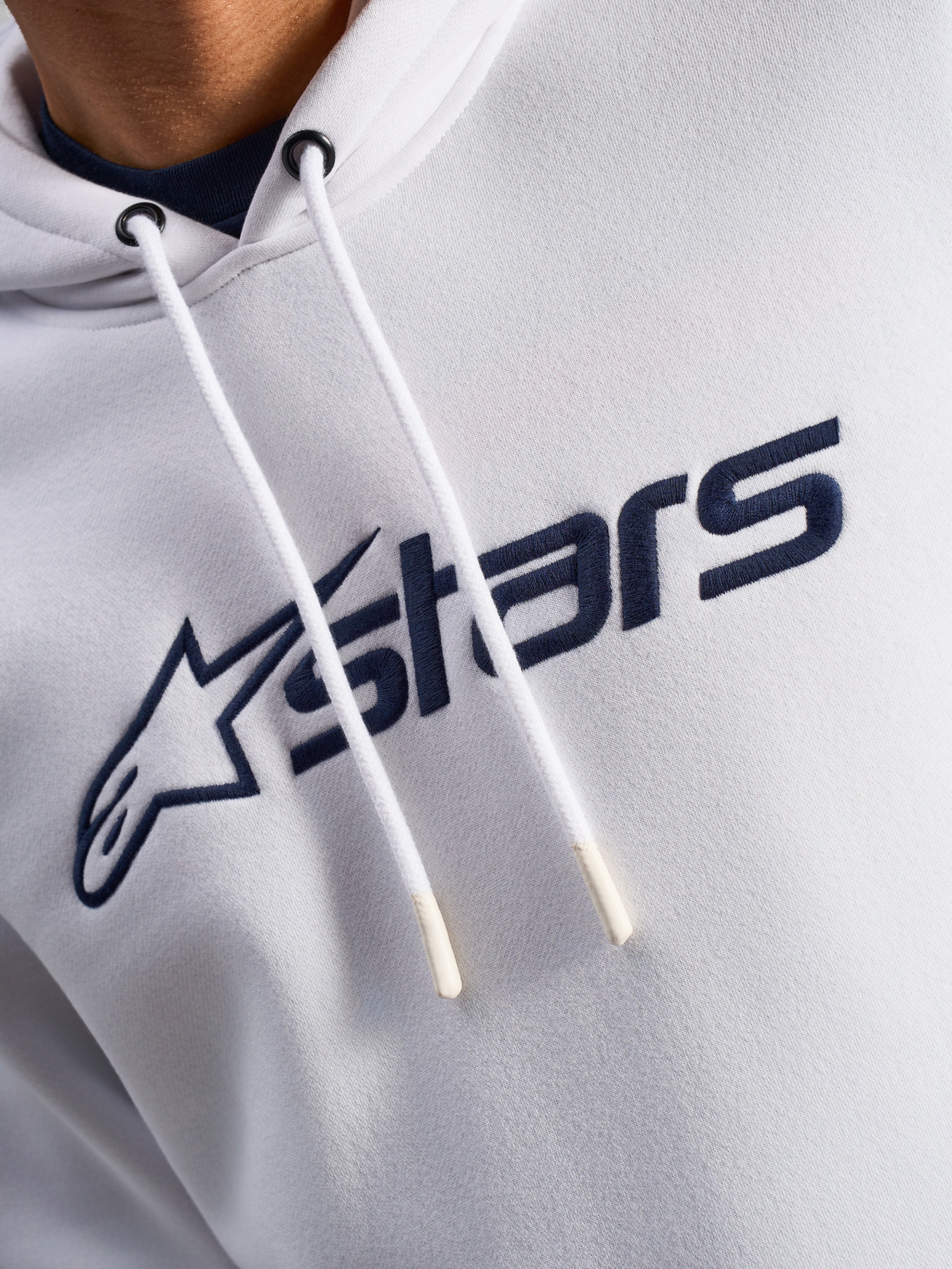 Alpinestars Blaze V3 Hoodie, biało-granatowa, zbliżenie na klatkę piersiową z granatowym nadrukiem logo z przodu i białymi sznurkami z powlekanymi końcówkami, codzienna odzież streetwearowa w stylu motorsportowym