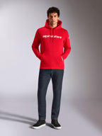 Alpinestars Linear Wordmark V3 Hoodie, casual streetwear, red with white linear wordmark on the chest, drawstring hood, front pouch pocket, worn with dark jeans and black sneakers, modern motorsport-inspired design