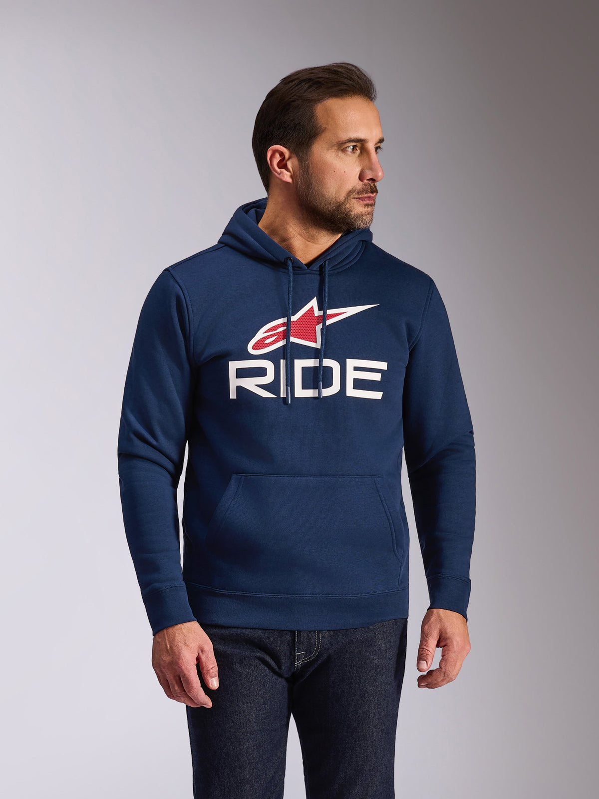 Alpinestars Ride V3 Hoodie, granatowa bluza z kapturem typu pullover, białe logo RIDE i czerwony symbol gwiazdy Alpinestars, kaptur ze sznurkami i podszewką z dżerseju, przednia kieszeń typu kangurka, nowoczesny streetwear inspirowany motorsportem