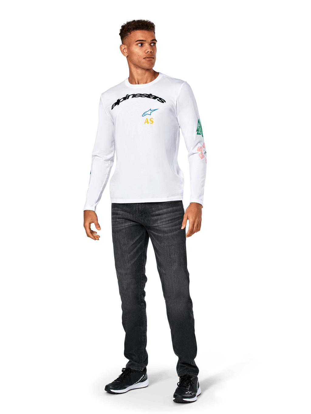 Alpinestars Brundo CSF Tee - Long Sleeve, biała, codzienna odzież sportowa, czarny napis „alpinestars” na piersi, niebieskie logo z gwiazdą i żółte inicjały „AS”, kolorowe grafiki na rękawie, noszona z ciemnymi dżinsami i czarnymi sneakersami