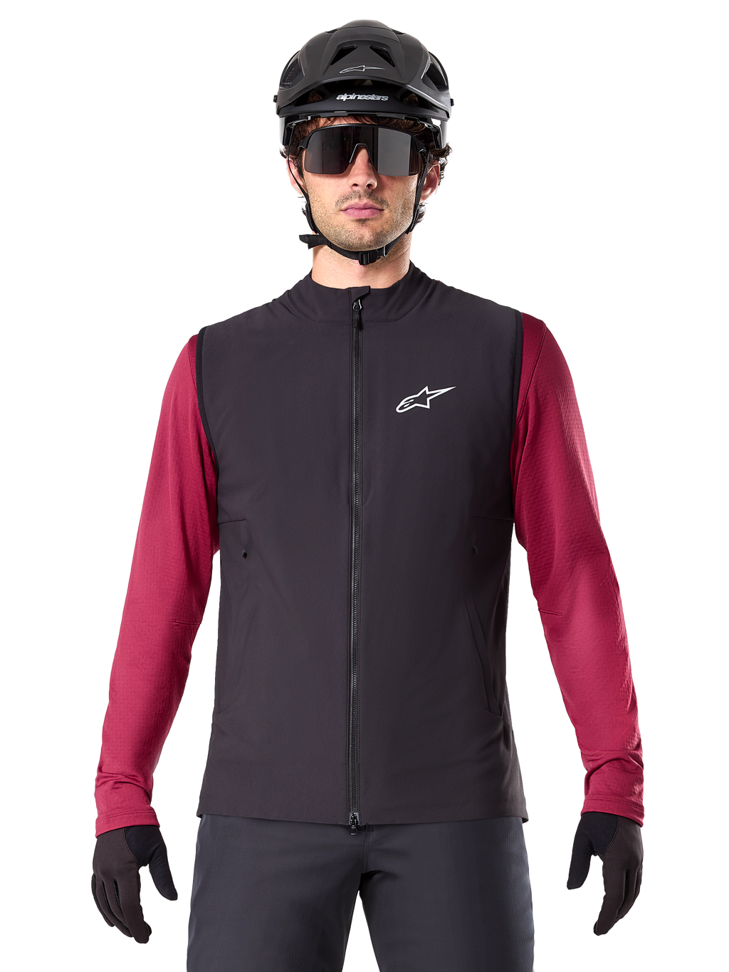 Kamizelka Alpinestars A-Dura Thermal, czarna ocieplana kamizelka rowerowa, na modelu z bordową koszulką z długim rękawem, czarnym kaskiem MTB i okularami przeciwsłonecznymi, białe logo na piersi, lekka ochrona termiczna do jazdy na rowerze górskim