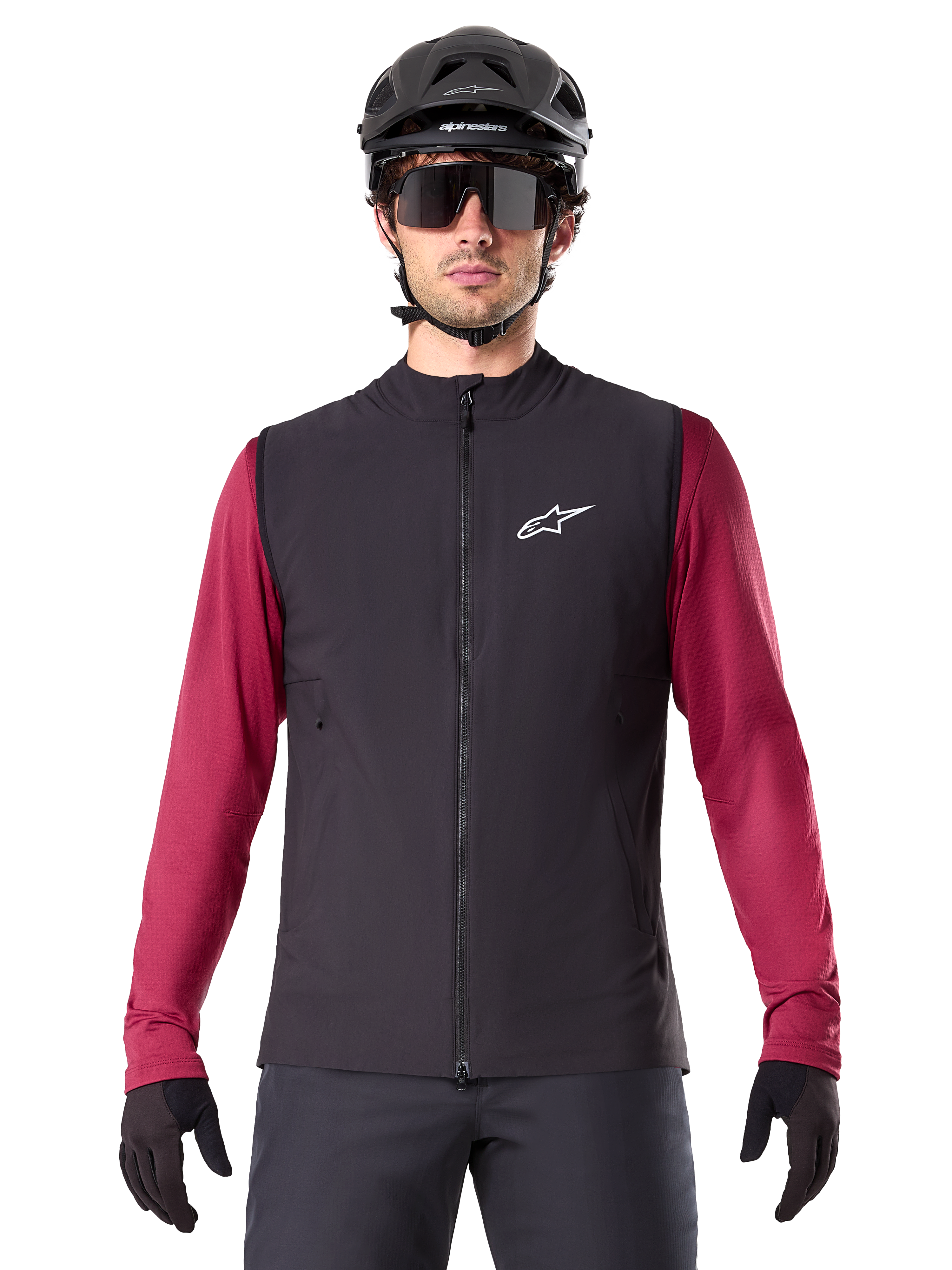 Kamizelka Alpinestars A-Dura Thermal, czarna ocieplana kamizelka rowerowa, na modelu z bordową koszulką z długim rękawem, czarnym kaskiem MTB i okularami przeciwsłonecznymi, białe logo na piersi, lekka ochrona termiczna do jazdy na rowerze górskim