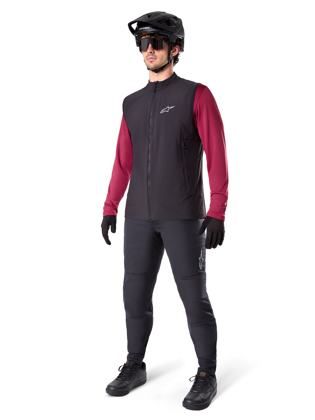 Alpinestars A-Dura Thermal Vest, czarna kamizelka rowerowa, noszona przez rowerzystę na bordową koszulkę z długim rękawem i czarne spodnie, z czarnym kaskiem MTB i rękawicami, zaprojektowana do jazdy na rowerze górskim w chłodne dni