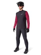 Alpinestars A-Dura Thermal Vest, czarna kamizelka rowerowa, noszona przez rowerzystę na bordową koszulkę z długim rękawem i czarne spodnie, z czarnym kaskiem MTB i rękawicami, zaprojektowana do jazdy na rowerze górskim w chłodne dni