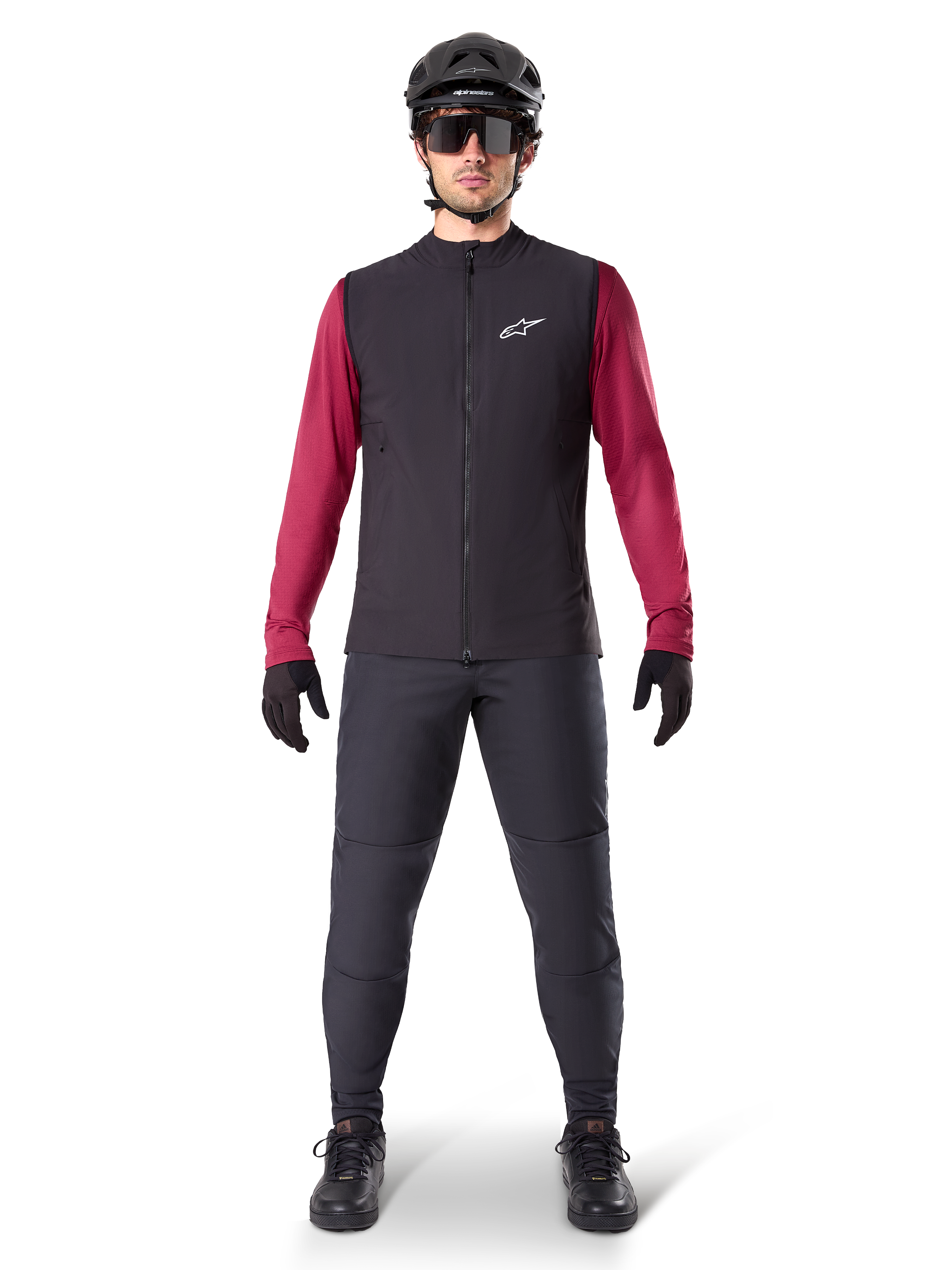 Kamizelka Alpinestars A-Dura Thermal, czarna kamizelka rowerowa założona na bordową koszulkę z długim rękawem, ciemnoszare spodnie MTB, czarny kask i okulary przeciwsłoneczne, techniczna odzież na rower górski do jazdy w zimne dni