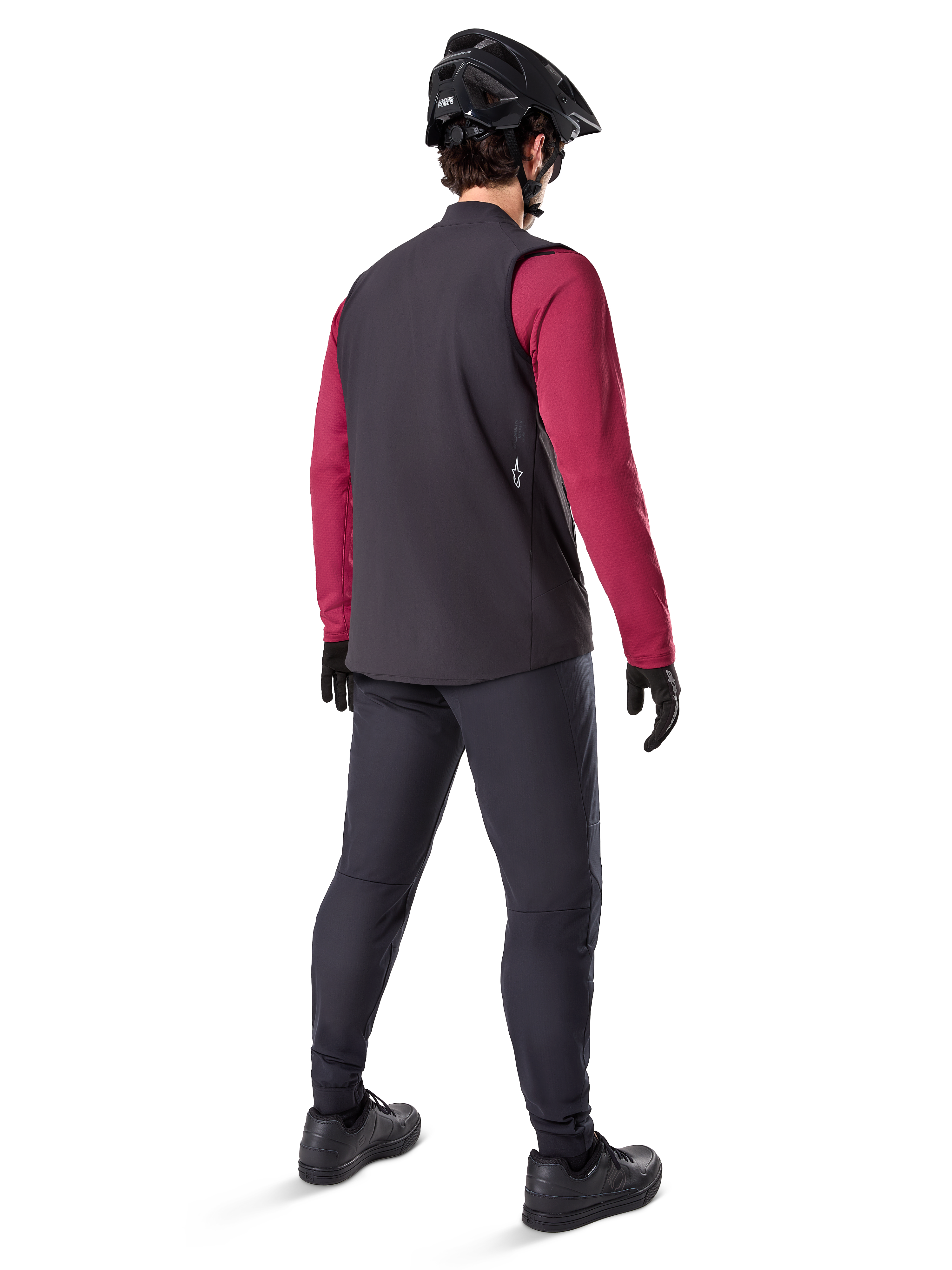 Alpinestars A-Dura Thermal Vest, czarna kamizelka rowerowa, widok z tyłu na modelu ubranym w bordową koszulkę z długim rękawem i czarne spodnie rowerowe, w zestawie z czarnym kaskiem MTB i rękawicami, odzież techniczna do jazdy w chłodne dni
