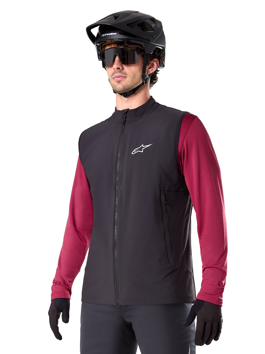 Alpinestars A-Dura Thermal Vest, czarna rowerowa kamizelka termiczna, noszona na bordowej koszulce z długim rękawem, z białym logo na piersi, w zestawie z czarnym kaskiem MTB i okularami przeciwsłonecznymi, izolująca warstwa techniczna do kolarstwa górskiego