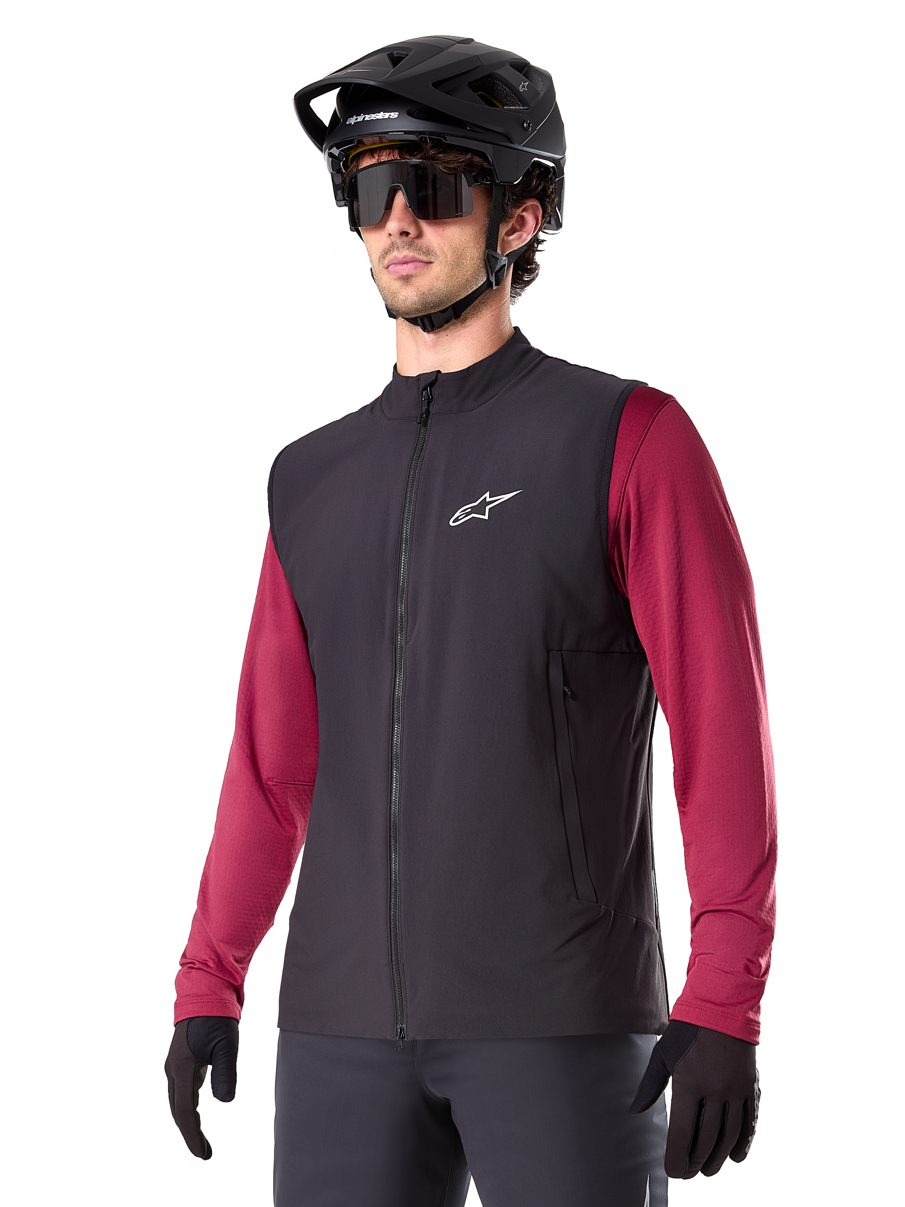 Alpinestars A-Dura Thermal Vest, czarna rowerowa kamizelka termiczna, noszona na bordowej koszulce z długim rękawem, z białym logo na piersi, w zestawie z czarnym kaskiem MTB i okularami przeciwsłonecznymi, izolująca warstwa techniczna do kolarstwa górskiego